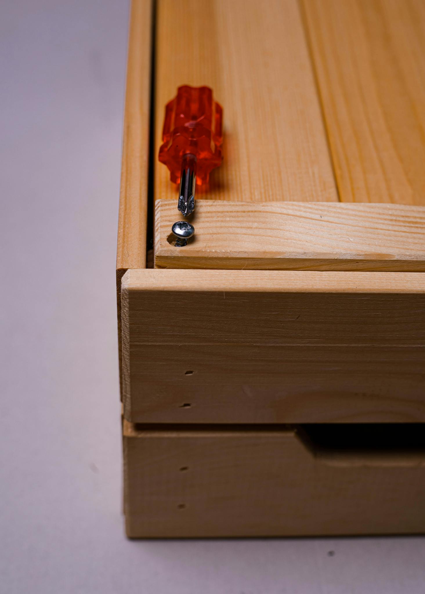 Detailed image of a screwdriver placed on a wooden box corner