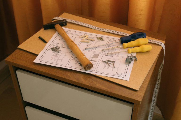 Flat lay of DIY furniture assembly with tools and instructions on a wooden desk.